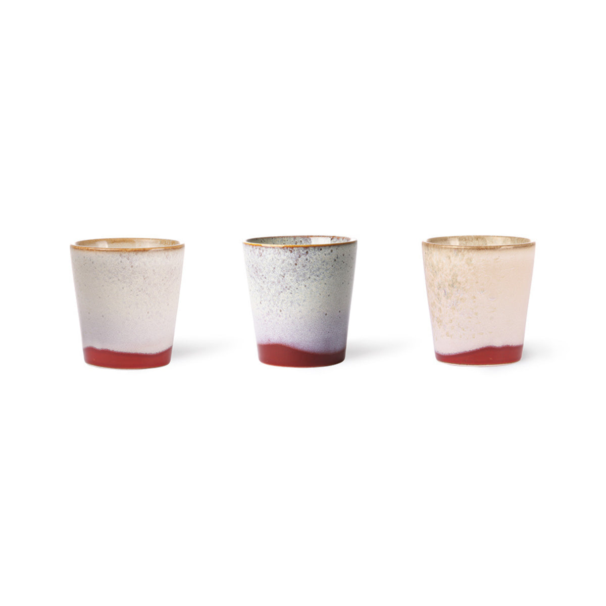 Drie HK Living 70s Ceramics Koffiekop Frost bekers met mat kleurverloop in aardetinten en een rode basis, geïnspireerd op retro stijl, naast elkaar geplaatst op een witte achtergrond.