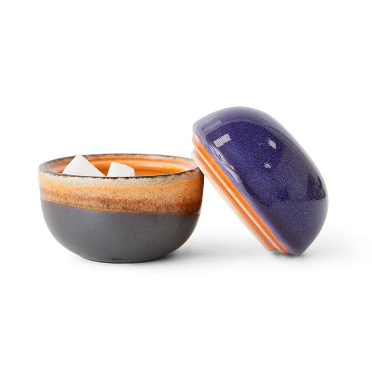 De HK Living 70s Ceramics Suikerpot 4PM is een kleine retro suikerpot met een veelkleurig paars en bruin glazuur. Het deksel zit vlakbij op een witte achtergrond, wat de klassieke jaren 70 stijl weerspiegelt, kenmerkend voor het HK Living merk.