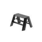 De Hasegawa Lucano Ladder 1 Step Zwart van Hasegawa is een compact, zwart opvouwbaar opstapkrukje met een gestructureerd bovenblad, geïnspireerd op Japans design en afgebeeld tegen een witte achtergrond.