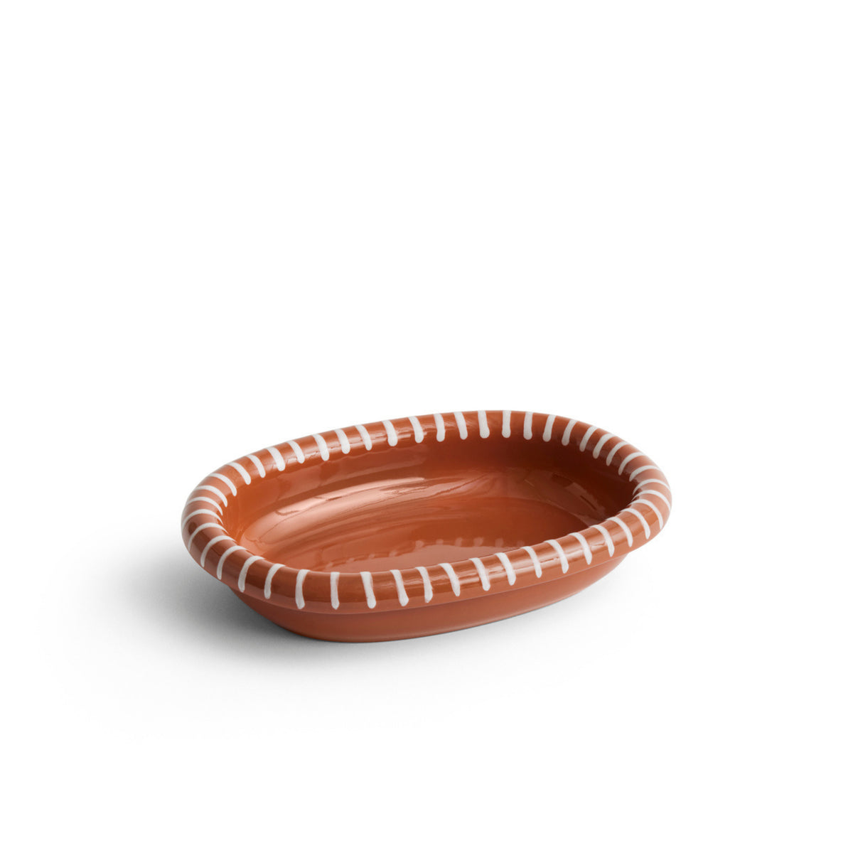 De Hay Barro Ovale Schaal Terracotta 20/27 van Hay is een kleine, ovale terracotta schaal met een glanzende afwerking en wit gestreept randpatroon, afgebeeld op een witte achtergrond.
