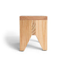 De Hay Manolito Kruk Bank Naturel Lang van Hay is een klein, minimalistisch houten krukje met een vierkante zitting, twee schuine poten en zichtbare natuurlijke nerfpatronen, afgebeeld tegen een witte achtergrond.
