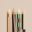 Vier hoge Hay Patroon Kaarsen Crème en Donker (set van 4) van het merk Hay, met geometrische patronen in beige, zwart, groen en bruin tegen een neutrale achtergrond-stijlvol als decoratie of geschenk.