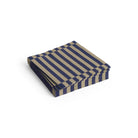 Een stapel Hay Pattern Papieren Servetten Donkerblauw Zand Streep 33/33 van Hay, met afwisselend donkerblauwe en zandkleurige strepen, is netjes gerangschikt op een witte achtergrond.