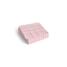 Een stapel Hay Pattern Papieren Servetten Lichtroze Rood Grid 25/25 van Hay, met een lichtroze-rood rasterdessin, is netjes gerangschikt op een witte achtergrond.