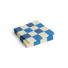 Een stapel Hay Patroon Papieren Servetten Off-white Blauw Ruit 33/33 van Hay, met een blauw en gebroken wit ruitjespatroon, geplaatst op een witte achtergrond.