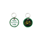 Twee ronde stoffen Hightide Stitch Work Sleutelhanger Fietssleutelhangers van Hightide, de ene met een groene omlijning, "Hightide" en een golfsymbool; de andere met een donkergroene achtergrond en geel retro fietsontwerp, beide met metalen ringen.