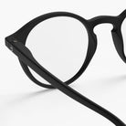 Close-up van de Izipizi Leesbril #D Zwart met heldere glazen, met het zwarte ronde montuur en de veren tegen een effen witte achtergrond - perfect voor mensen met ouderdomsverziendheid.