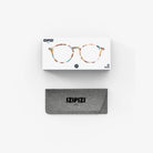 Een Izipizi Leesbril #D Blue Tortoise leesbril met rond montuur is afgebeeld boven een grijs stoffen etui, beide op een witte achtergrond.