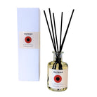 Naast een witte doos staat een fles Matriks Fragrances Diffuser Sandalwood Noir van 200 ml met zwarte rietstokjes. Beide zijn voorzien van een rood rond etiket met de tekst ‘Sandalwood No 12’ en zijn vervaardigd door Matriks Fragrances voor een elegante uitstraling.