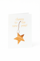 Stuur feestelijke wensen met de Matriks Nieuwjaarskaart Cheers to the New Year! kaart, met een uniek kerstbal houten ster ornament en "cheers to the new year!" in geel op een witte achtergrond.