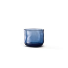 De Paveau Swirl Waterglas Midnight Blauw 24 cl van Paveau is een doorschijnende donkerblauwe glazen beker met een organische golvende vorm, elegant afgebeeld tegen een witte achtergrond.
