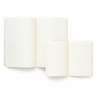 Twee open, gelinieerde notitieboeken liggen op een wit oppervlak, waarbij het kleinere Penco Notitieboek Groen A6 het grotere notitieboek gedeeltelijk overlapt. Beide zijn voorzien van blanco, crèmekleurige pagina's.