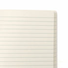 Een close-up van de linkerbovenhoek van een open, blanco, gelinieerd Penco Notitieboek Groen A6 van Penco met crèmekleurige pagina's, afgebeeld tegen een witte achtergrond.