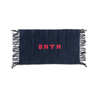 De Puebco Badmat Gerecycleerd Garen Blauw 75/45 is een rechthoekige, donkerblauwe handgeweven mat met franje aan de randen en 'BATH' in dikke rode letters in het midden.