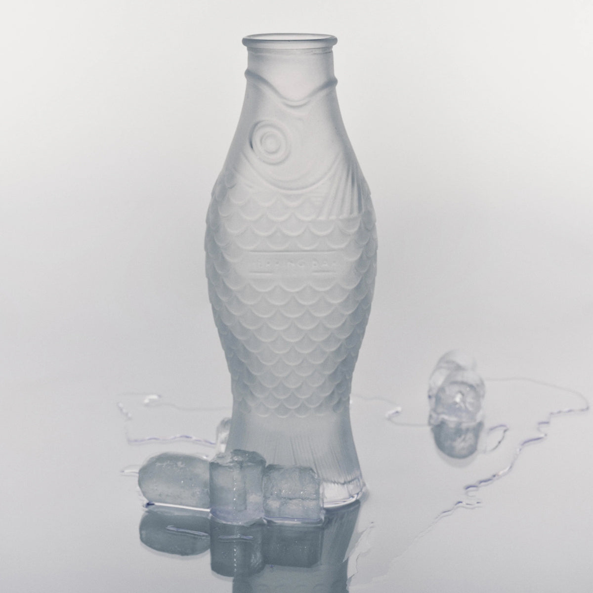 De Serax Fish & Fish Karaf Frosted 85 cl, in de vorm van een vis en rechtopstaand tussen smeltende ijsblokjes, is het perfecte hoogtepunt uit de Serax collectie.