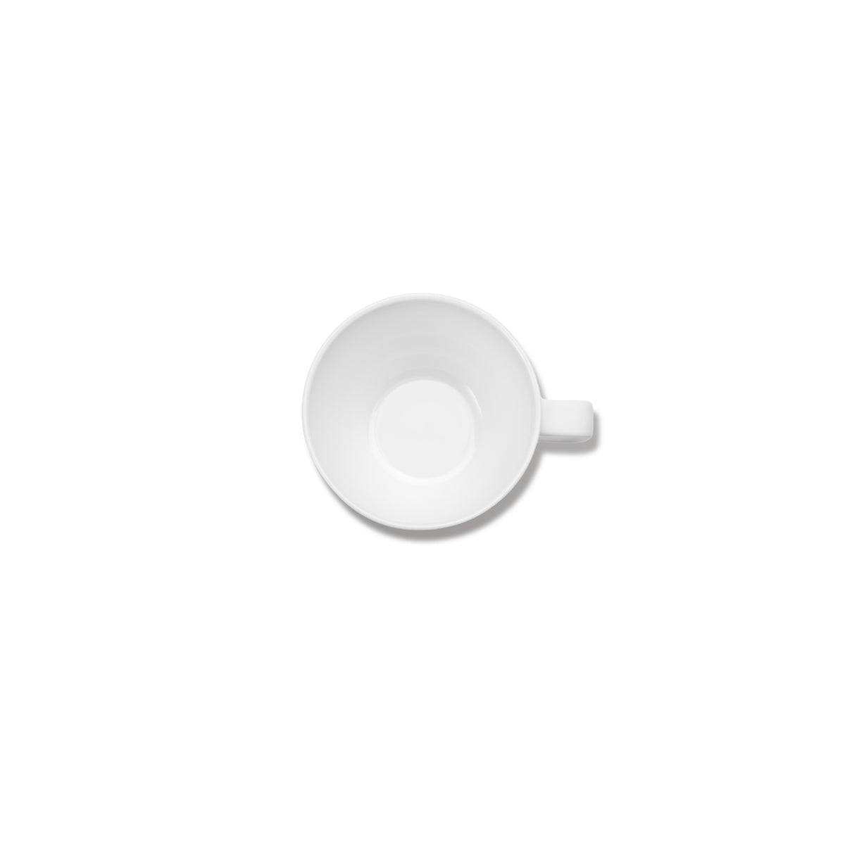 Een Serax Base Koffiekop met Oor 30 cl, gemaakt door Serax, is van bovenaf gefotografeerd op een effen witte achtergrond. De lege witte beker, met het handvat naar rechts, benadrukt het verfijnde porseleinen vakmanschap.