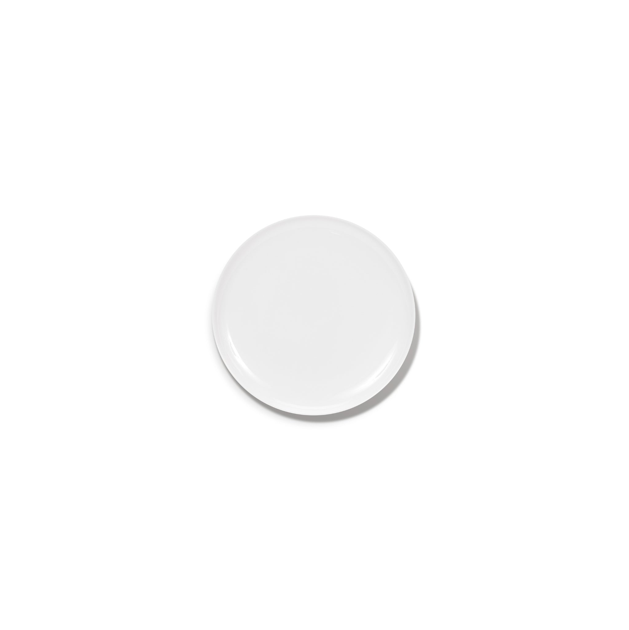 Een effen, rond wit Serax Base Laag Bord D16 bord is gecentreerd op een witte achtergrond, waardoor een vage schaduw ontstaat en de verfijnde elegantie van Serax vakmanschap prachtig tot zijn recht komt.