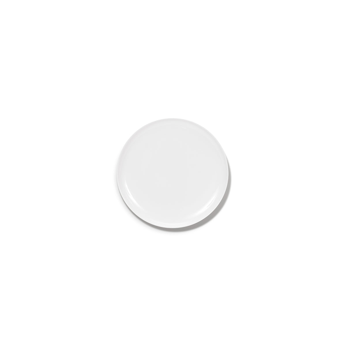 Een effen, rond wit Serax Base Laag Bord D16 bord is gecentreerd op een witte achtergrond, waardoor een vage schaduw ontstaat en de verfijnde elegantie van Serax vakmanschap prachtig tot zijn recht komt.