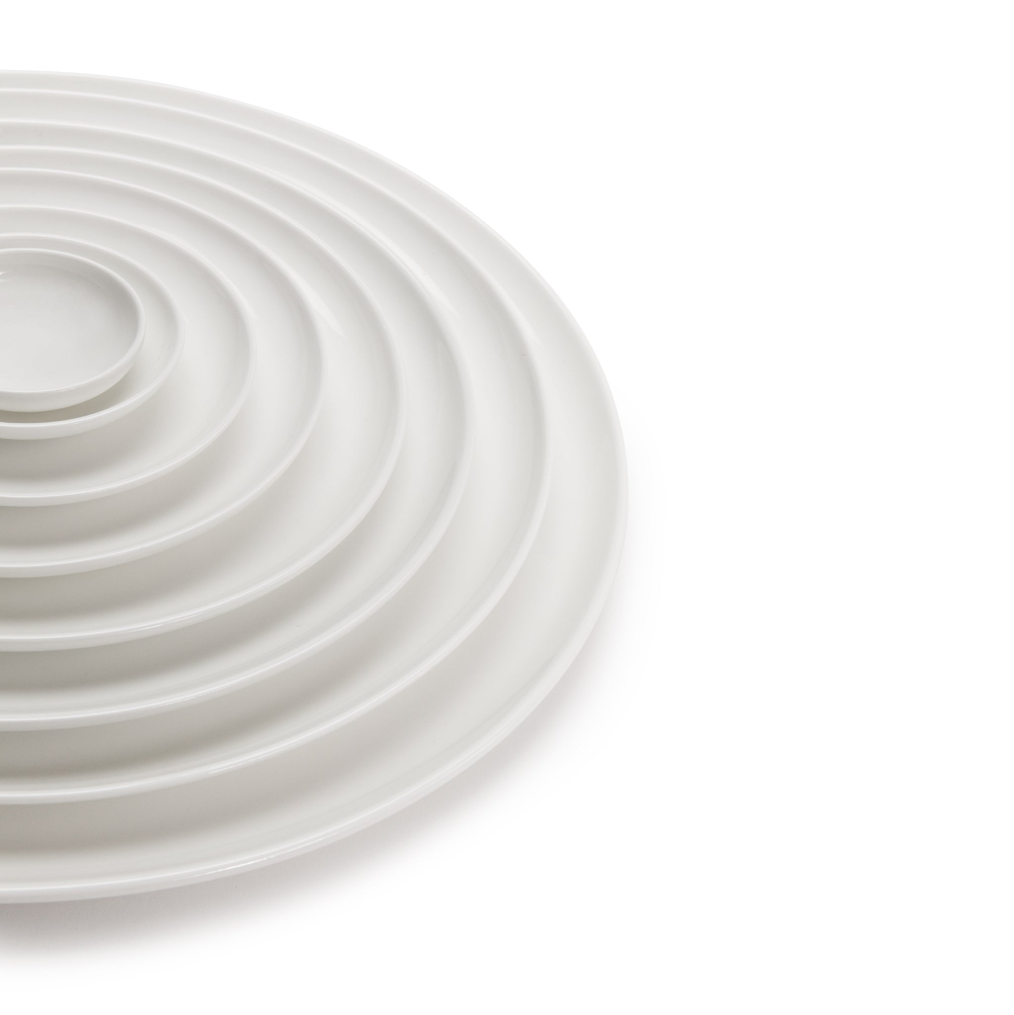 Een stapel witte Serax Base Laag Bord D28 borden van Serax, concentrisch gerangschikt op een witte achtergrond waarbij de rechterkant uit het frame steekt.