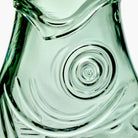 Close-up van het gestructureerde, transparant groene glazen oppervlak met wervelende, golfachtige patronen van de Serax Fish & Fish Karaf Groen 85 cl.