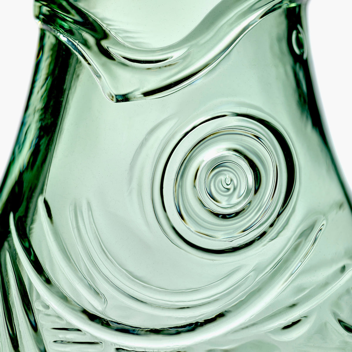 Close-up van het gestructureerde, transparant groene glazen oppervlak met wervelende, golfachtige patronen van de Serax Fish & Fish Karaf Groen 85 cl.