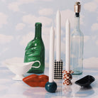 Een stilleven met hoge witte kaarsen in Serax Wouters & Hendrix Chessboard Kandelaars (set van 3), lege groene en heldere flessen, een witte juskom, een rood lipvormig object en een klein zwart schaaltje tegen een hemelsblauwe bewolkte achtergrond.