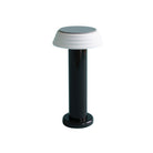 De Sowden PL1 Lamp LED Oplaadbaar Zwart van Sowden heeft een glanzend zwarte cilindrische voet en een witte, licht uitlopende ronde lampenkap, geïnspireerd op de Memphis Design Movement en afgebeeld tegen een effen witte achtergrond.