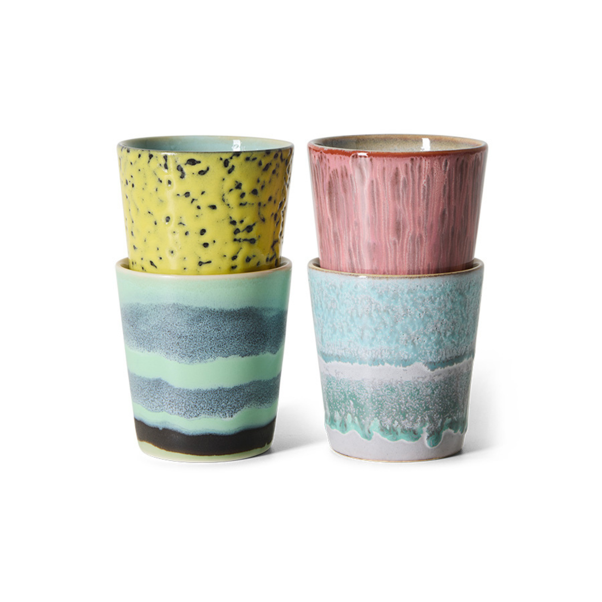 Twee stapels HK Living 70s Ceramics Koffiemok kopjes: linker stapel is geel met zwarte spikkels over groen met blauwe strepen; rechter stapel is roze over turkoois met golvende patronen. Verkocht als set van 4 door HK Living.