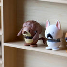 Op een houten plank staan twee kleine dierfiguurtjes met verende lichamen: een bruine egel en de Hoptimist Franse Bulldog Hond Wit/Zwart XS van Hoptimist, een ideaal cadeau voor hondenliefhebbers.
