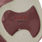 Close-up van de basis van een Serax Marni After Midnight Uil Vaas Aubergine XS, met glanzende kastanjebruine en crèmekleurige tinten. "MARNI" in rood en "SERAX" in zwart zijn op het oppervlak gedrukt.