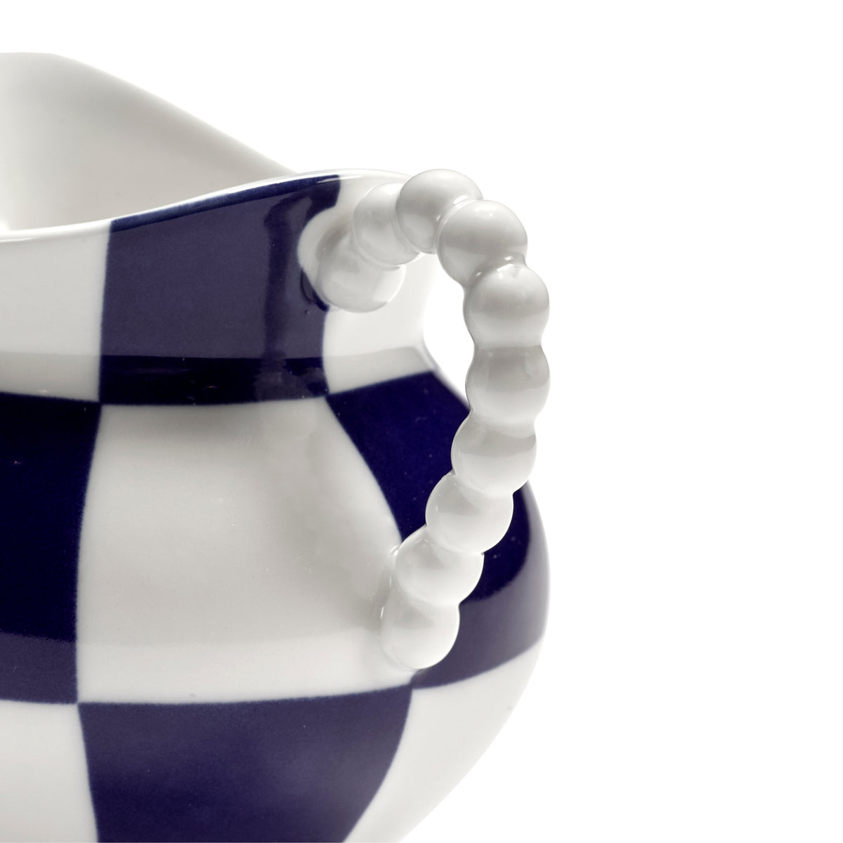 Close-up van het Serax Wouters & Hendrix Fête Des Bêtes Melkkannetje Blauw Wit, met een kralenhandvat en een vet blauw-wit dambordpatroon op een witte achtergrond.