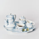 De Serax Wouters & Hendrix Fête Des Bêtes Koffiekop + Schotel Lichtblauw heeft een blauw-wit wolkenluchtontwerp, uitgestald met koffie en verpakte snoepjes op een bijpassend dienblad tegen een witte achtergrond.